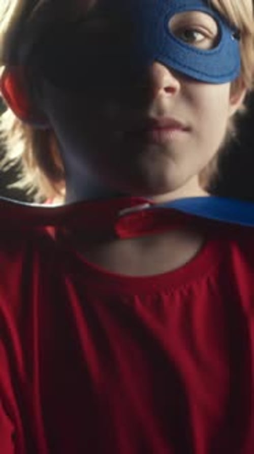 Vertical of Little Superhero Posing on Dark Studio Background