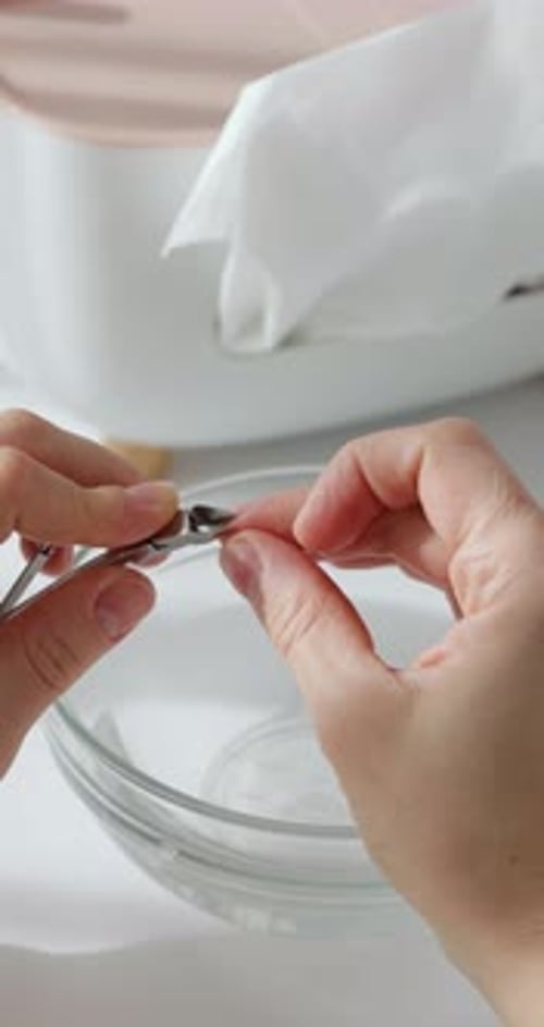 Woman Clips Nail at Home in Clear Bowl