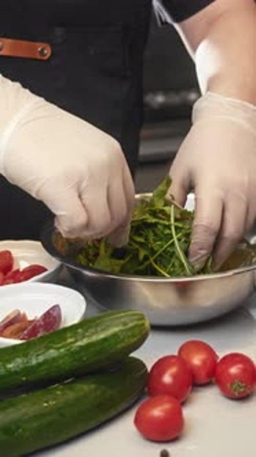 The Gloved Hands of a Skilled Chef Expertly Prepare a Delectable and Juicy Salad Seasoned with a