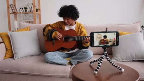 Woman Plays Guitar While Recording on Phone