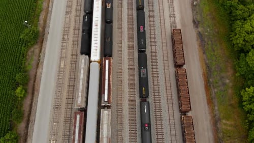 Vista aérea de 4k de vários trens sentados em uma estação de trem enquanto revela uma longa ferrovia reta