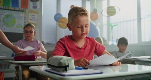 Un enseignant donne des articles avec les résultats des tests scolaires Un garçon intelligent se réjouit et célèbre son excellente note