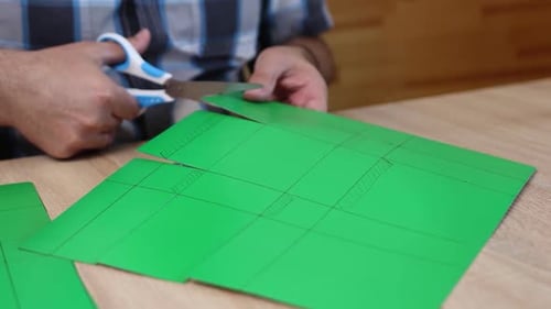 Person Cutting Green Paper with Scissors, Craft Activity