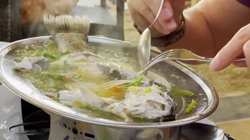 Steamed Fish with Lime Pepper and Various Food Ingredients on a Table with Thai Food Dishes Eating