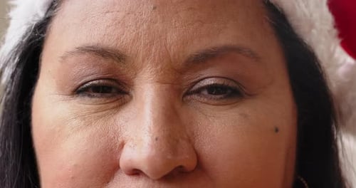 At christmas, Close-up of woman wearing Santa hat, smiling warmly during holiday celebration