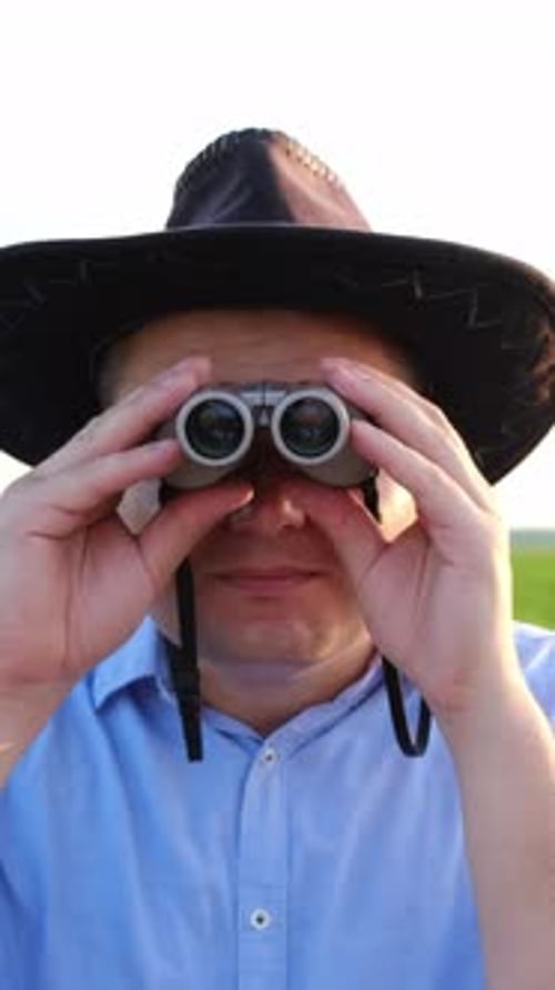 Man Wearing Cowboy Hat Viewing Through Binoculars