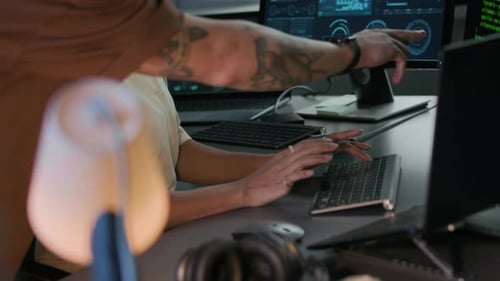 Junger männlicher Programmierer bringt seiner jüngeren Kollegin im Büro das Tippen bei