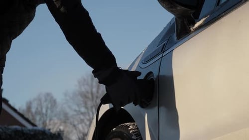 Electric Car Charging Cable Being Removed on Winter Day