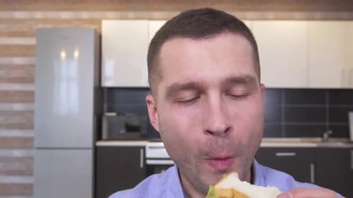 Young Adult Man Enjoys Eating a Sandwich