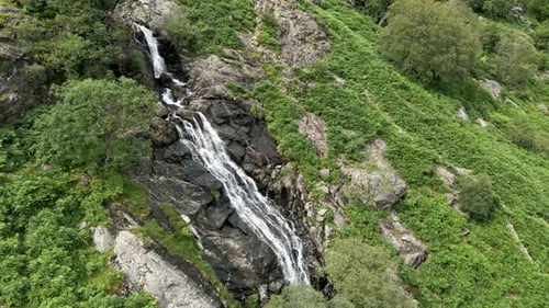 Aerial View of Waterfall Cascading Down Rocky Hillside