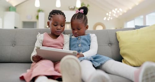 Girls Sitting on Couch Looking at Tablet