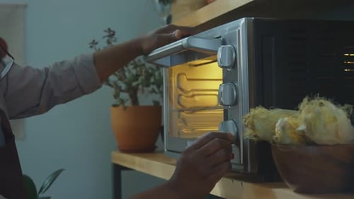 Man Turns On Countertop Oven on Kitchen Shelf