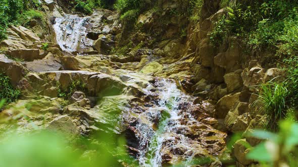 Water cascades down rocky waterfall in Rwanda Volcanoes National Park ...