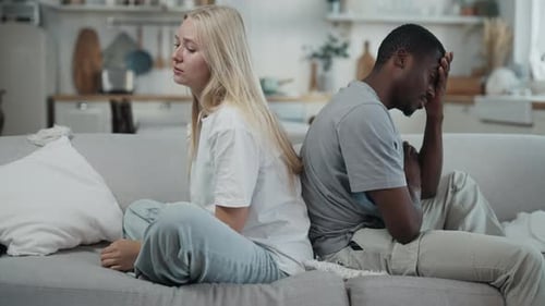 Couple Sitting Back to Back on Couch Indoors