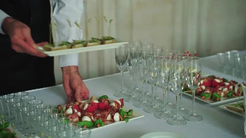 Server Prepares Finger Foods and Table Setup Attendant Organizes Small Bites for Guests with