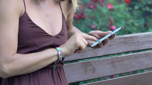 Woman Browsing Internet On Tablet Sitting On Bench In City