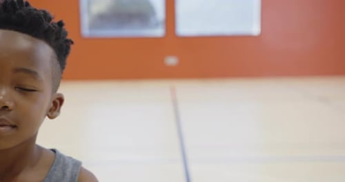 In school gym, boy standing and looking, focusing on camera