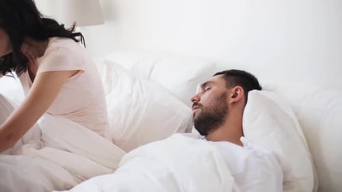 Les gens, le ronflement et les problèmes de sommeil Concept - Une femme en colère réveille un homme endormi dans son lit