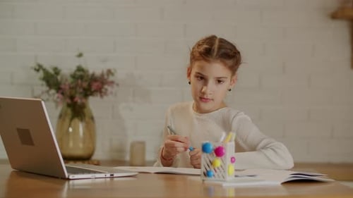 Girl Writes In Notebook While Looking At Laptop