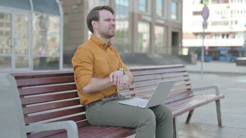 Young Adult Using Laptop on Urban Park Bench