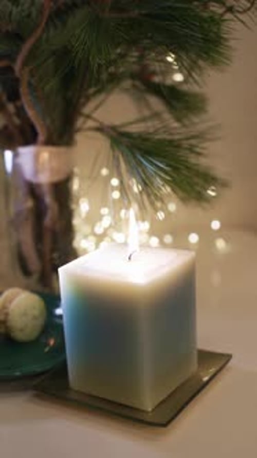 Burning candle close-up. Decorated christmas tree on background. Winter holidays concept. Celebratin