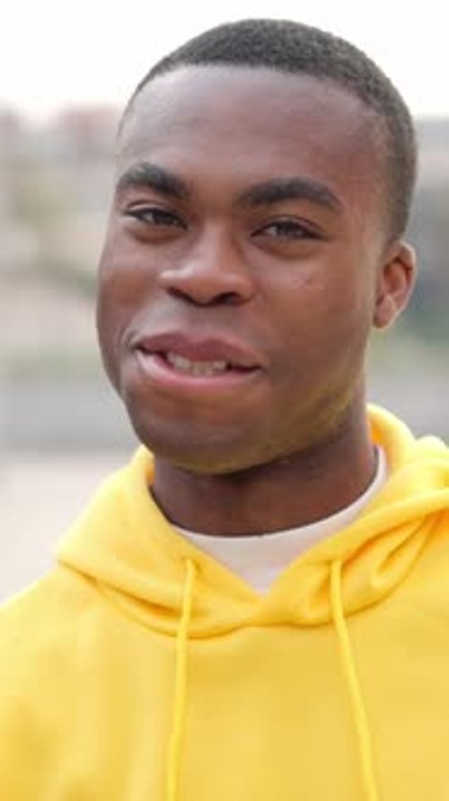 Jeune homme africain debout à l'extérieur et souriant