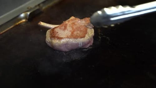 Cooking a slice of meat on a cooking stove at a restaurant