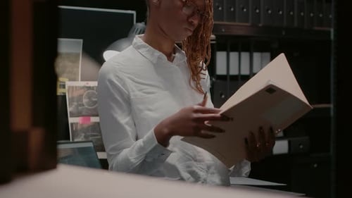 Woman Looks at File at Her Workplace