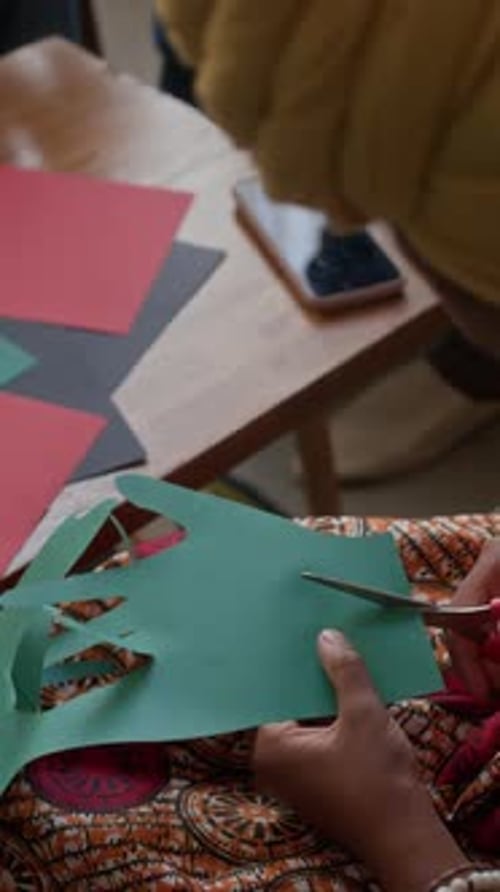 Vertical of African American Girl Cutting Paper Hand for Kwanzaa Celebration