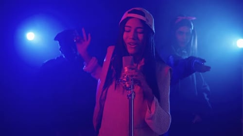 Young Woman Singing Into Microphone on Stage