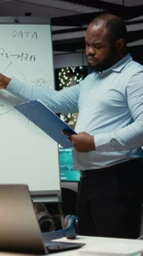 Vertical Video African American Worker Summarizing Insights and Reports on a White Board