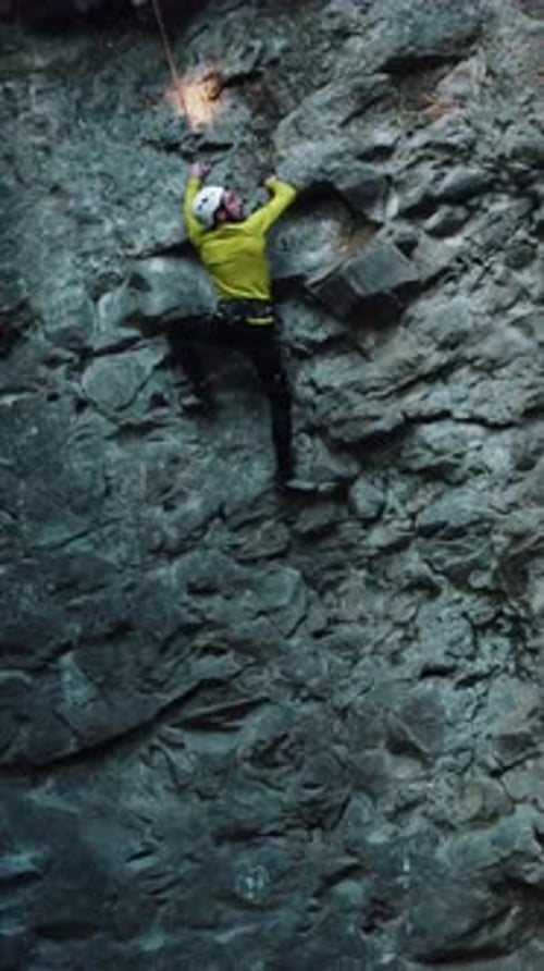 Aerial View of Professional Active Sportsman Climber in Bright Sportswear Climbing High Stone Rock