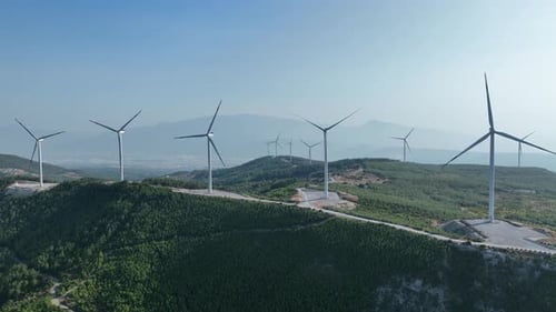 Aerial View Of Wind Energy Turbine Rotating In The Wind Among Green Hills