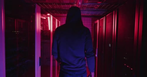 Hooded Figure Walking Through Server Room at Night