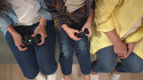 Top View Close Up Shot of Grandmother Daughter and Kid on the Sofa Playing Video Game with Joysticks