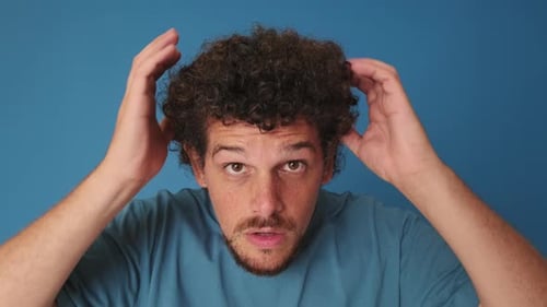Close-up of man looking at the camera as if in mirror isolated on blue background
