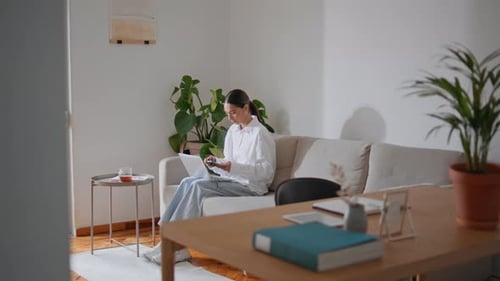 Entspannte Geschäftsfrau arbeitet alleine auf dem Sofa zu Hause. Konzentrierte Frau lernt Computer online checken