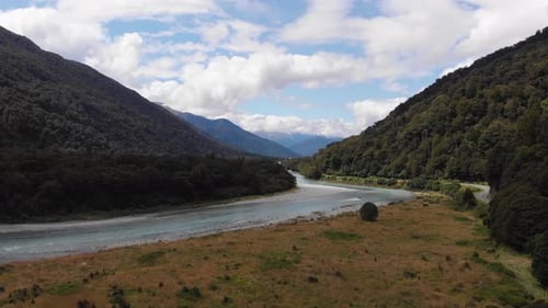 Drone view of a river in beautiful scenic valley and speedboat in the distance. Shot on a cloudy sum