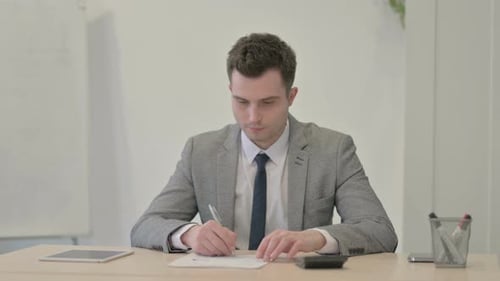 Young Adult Man Working on Report in Office