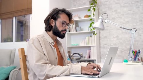 Man Working on Laptop at Bright Home Office