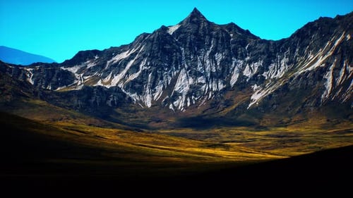 Majestic Mountain Peak Rises Above Lush Valley Under Clear Blue Sky