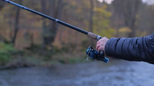 Person Fishing with Rod and Reel in River