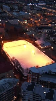 Vertical drone shot circling a illuminated ice hockey rink, dark ...