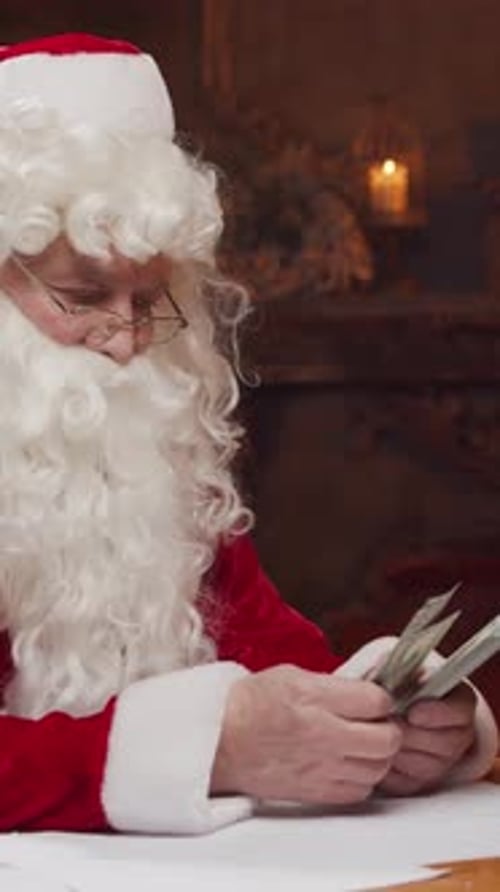 Santa Claus's Workshop Santa is Busy Wrapping a Gift at the Table with a Fireplace and Christmas