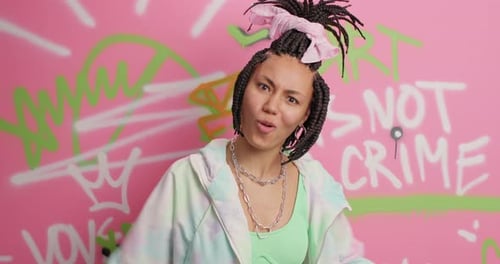 Excited woman cheering and gesturing in front of graffiti