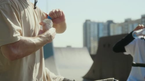 Young BMX Rider Drinking Water after Training with Friend at Skate Park