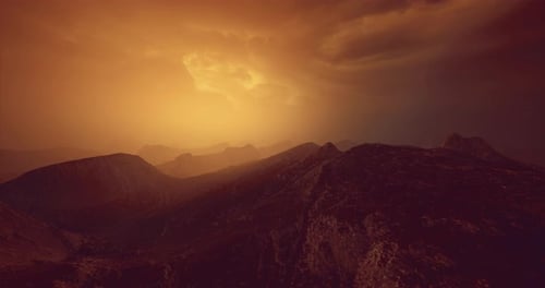 Dramatic Sunset Over Mountain Landscape with Clouds and Warm Light