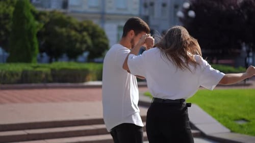 Side View Young Woman Learning Riding Skateboard with Man Helping Holding Hand Walking Aside