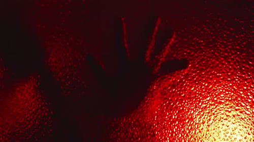 Terrifying silhouette of possessed killer creeps on glass, slowly opens door in the dark under omino