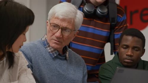 Senior Male Professor Pointing at Laptop Helping Students with Study at College